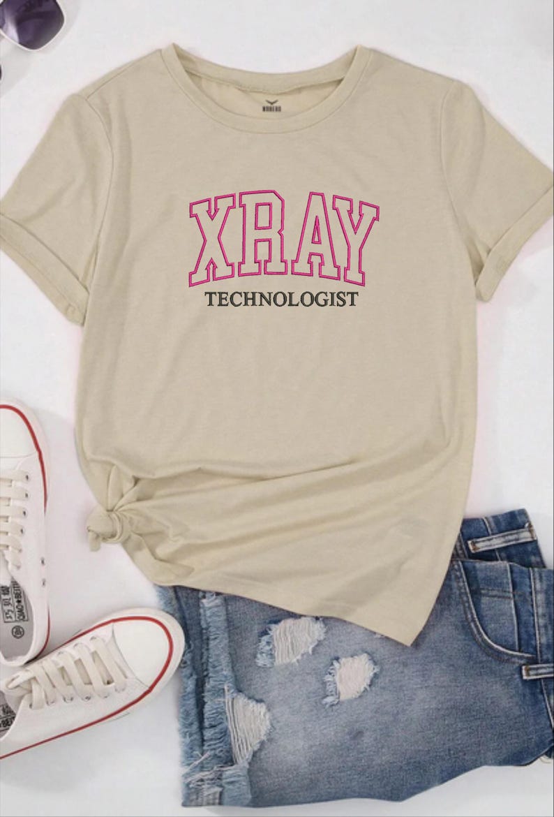 K&ouml;nnte beinhalten: Ein beiges T-Shirt mit einem rosa Umriss des Wortes "XRAY" und dem Text "TECHNOLOGIST" darunter.
