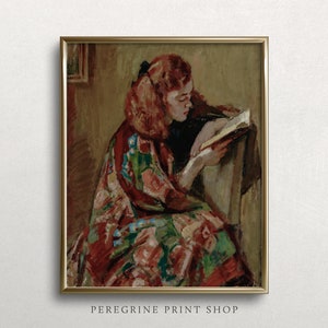 May include: A painting of a young woman with red hair sitting in a chair and reading a book. She is wearing a colorful patterned robe. The painting is framed in gold.