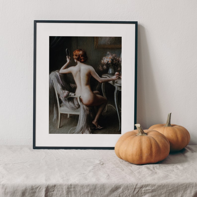 May include: A framed painting of a woman sitting in a chair, looking at a mirror. She is nude and has red hair. The painting is set in a dimly lit room with a vanity table in the background.
