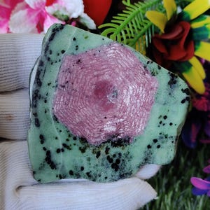 Puede incluir: Una piedra preciosa verde y rosa con un patr&oacute;n de estrella. La piedra preciosa es rugosa y tiene un aspecto natural sin pulir.