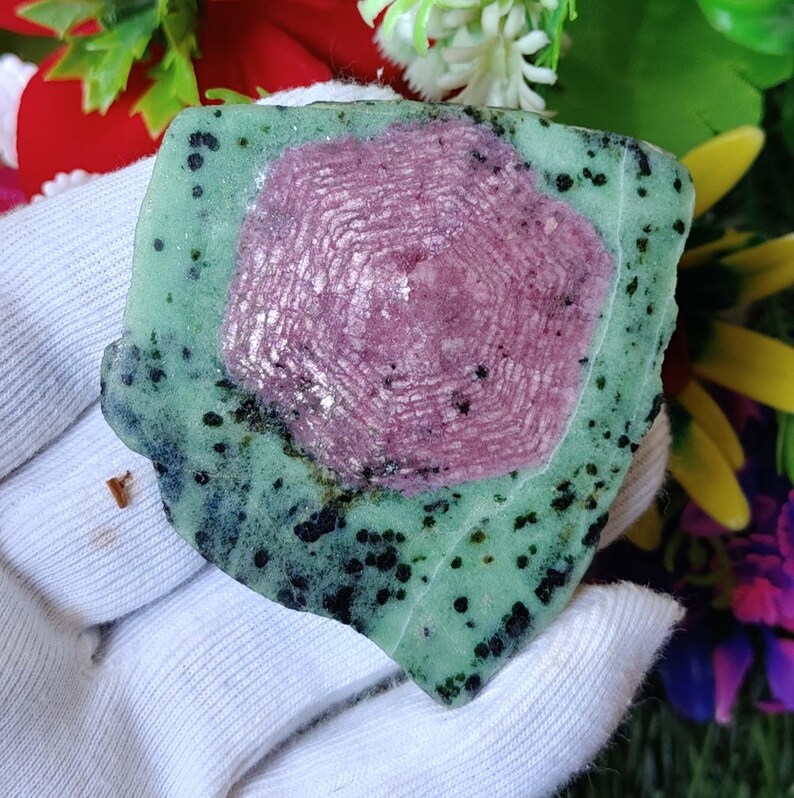 Pu&ograve; includere: Primo piano di una gemma verde e rosa con un motivo esagonale. La gemma &egrave; circondata da una matrice verde scuro.
