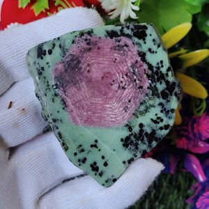 Pu&ograve; includere: Una pietra preziosa verde e rosa con macchie nere. La pietra preziosa ha un motivo a stella al centro.