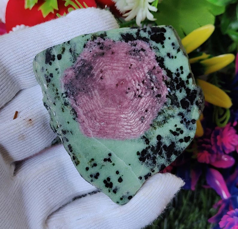 Pu&ograve; includere: Una pietra preziosa verde e rosa con macchie nere. La pietra preziosa ha un motivo a stella al centro.