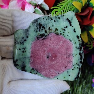Puede incluir: Una piedra preciosa verde y rosa con un patr&oacute;n &uacute;nico de estrella. La piedra preciosa tiene una forma irregular y una textura rugosa.