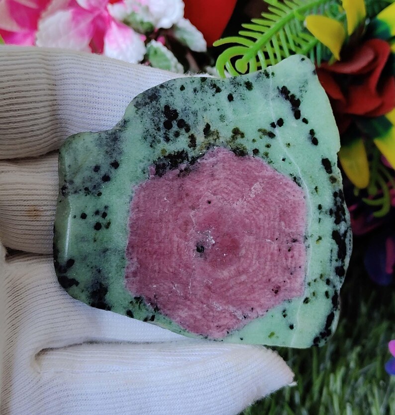 Puede incluir: Una piedra preciosa verde y rosa con un patr&oacute;n &uacute;nico de estrella. La piedra preciosa tiene una forma irregular y una textura rugosa.