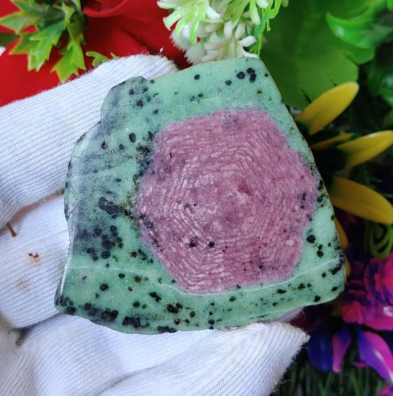 Pu&ograve; includere: Una pietra preziosa verde e rosa con un motivo unico. La pietra preziosa ha uno strato esterno verde con macchie nere e un centro rosa con un motivo a stella.