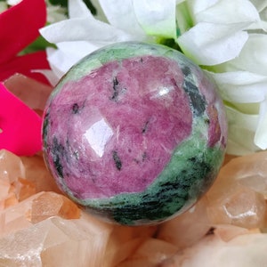 May include: A green and pink sphere of polished ruby zoisite, also known as anyolite, with a smooth, glossy finish. The sphere is approximately 2 inches in diameter.