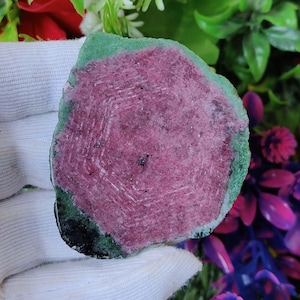 Könnte beinhalten: Ein rosa-grüner Edelstein mit einem sechseckigen Muster. Der Edelstein ist geschliffen und poliert und hat eine glatte Oberfläche.