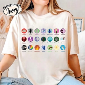 May include: Ivory-colored Comfort Colors t-shirt with a graphic featuring colorful circular icons and text. The icons represent various concepts like "Empath," "Shade," and "Conjurer." The shirt has a relaxed fit.
