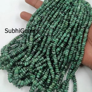 Peut inclure: Un ensemble de perles de pierres précieuses vert émeraude. Les perles sont petites, cylindriques et enfilées ensemble. L'image comprend le texte "SubhiGems". Les perles sont d'un vert profond et riche.