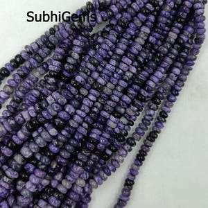 Puede incluir: Hebras de cuentas de piedras preciosas moradas y negras. Las cuentas son pequeñas, cilíndricas y pulidas. La imagen incluye el texto "SubhiGems". Las cuentas están ensartadas, listas para la creación de joyas.