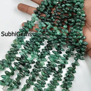 Peut inclure: Brins de perles de pierres précieuses vert émeraude. Les perles sont en forme de goutte et enfilées ensemble. L'image comprend le texte "SubhiGems". Les perles sont d'un vert profond et riche et semblent polies.