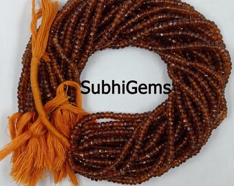 May include: A bundle of faceted, brown gemstone beads, arranged in a circular pattern. An orange tassel is attached to the beads. The text "SubhiGems" is visible.