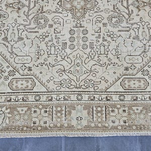 K&ouml;nnte beinhalten: Nahaufnahme eines beige-braunen Teppichs mit Muster. Der Teppich weist ein kompliziertes Design mit floralen und geometrischen Motiven auf. Der Rand ist in einem dunkleren Braunton gehalten und der Teppich hat einen Used-Look.