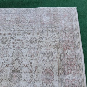 May include: A vintage rug with a floral pattern in shades of pink and white. The rug has a faded, distressed look, giving it a unique and antique feel.