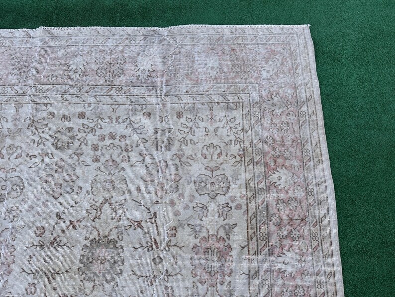 May include: A vintage rug with a floral pattern in shades of pink and white. The rug has a faded, distressed look, giving it a unique and antique feel.