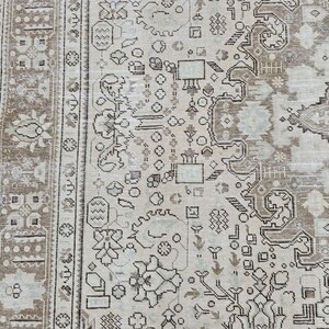 K&ouml;nnte beinhalten: Ein Abschnitt eines beigefarbenen und braunen Vintage-Teppichs mit einem komplizierten, sich wiederholenden Muster. Der Teppich weist florale und geometrische Designs in Beige-, Braun- und Graut&ouml;nen auf. Der Rand hat ein dunkleres braunes Blumenmuster.