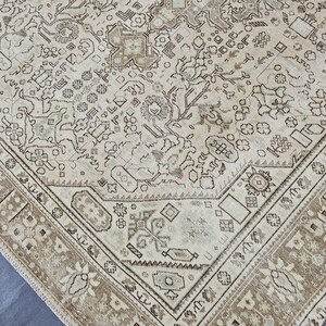 K&ouml;nnte beinhalten: Ein antiker beigefarbener Teppich mit einem detaillierten, komplizierten Muster. Der Teppich hat ein zentrales Design mit floralen und geometrischen Elementen, das von einem braunen Rand umrahmt wird. Die Gesamt&auml;sthetik ist Vintage und klassisch.