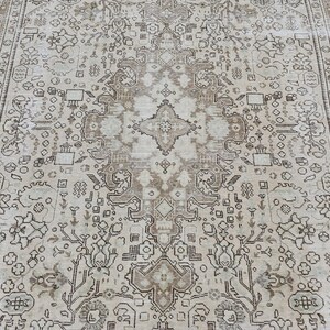 K&ouml;nnte beinhalten: Ein Teppich im antiken Stil mit einem zentralen Medaillon-Design. Der Teppich hat einen cremefarbenen Hintergrund mit aufwendigen Mustern in Braun- und Beiget&ouml;nen. Der Rand hat ein detailliertes Blumendesign.