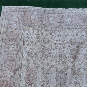May include: A vintage rug with a floral pattern in shades of pink and white. The rug has a faded, distressed look, giving it a unique and antique feel.