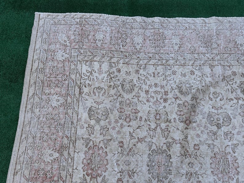 May include: A vintage rug with a floral pattern in shades of pink and white. The rug has a faded, distressed look, giving it a unique and antique feel.
