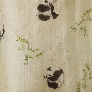 Pu&ograve; includere: Un tessuto beige chiaro caratterizzato da un sottile motivo floreale in rilievo su tutta la superficie. Il materiale &egrave; decorato con illustrazioni stampate di panda bianchi e neri in varie pose, intervallate da delicati rami e foglie di bamb&ugrave;.