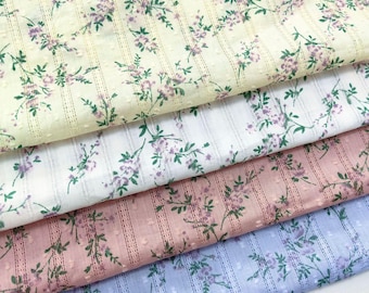 May include: Four folded layers of fabric featuring a delicate floral pattern with small purple flowers and green leaves. The material has a subtle vertical striped texture with tiny raised dots, available in pale yellow, white, dusty pink, and light blue.