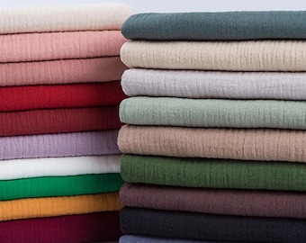 May include: Two vertical stacks of folded fabric featuring a crinkled, textured surface. The left stack includes shades of cream, pink, red, purple, white, green, yellow, and maroon. The right stack features dark teal, beige, gray, sage, tan, olive, brown, black, and blue.