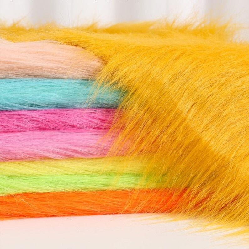 May include: A stack of long-pile faux fur fabric in vibrant colors including mustard yellow, peach, turquoise, hot pink, lime green, and bright orange. Each layer features a soft, shaggy texture with long, flowing synthetic fibers.
