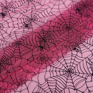 Könnte beinhalten: Rosa-schwarzer Spinnennetzstoff mit einem Verlaufseffekt. Der Stoff besteht aus einem durchsichtigen Netzmaterial und weist ein sich wiederholendes Muster aus Spinnennetzen und Spinnen auf.