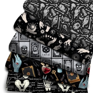 Pode incluir: Cinco amostras de tecido com fundos pretos e várias ilustrações brancas e cinzas. As ilustrações incluem ossos, mãos, luas, estrelas, cartas de tarô, um gato preto, uma caveira, uma garrafa de poção, uma chave e um livro. O texto nas cartas de tarô diz "BLACK CAT".