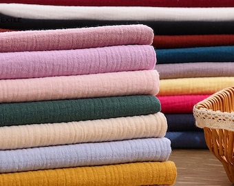 May include: A stack of 10 different colored fabric swatches. The swatches are all made of a soft, textured material. The colors include pink, purple, beige, green, cream, light blue, yellow, and brown.
