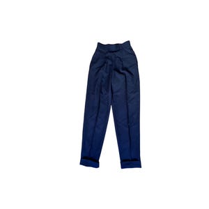 May include: Navy blue high-waisted pants with a pleated front and cuffed hems. The pants have a tailored fit and a classic design. The dark blue color and clean lines make them suitable for various occasions. These pants are a versatile addition to any wardrobe.