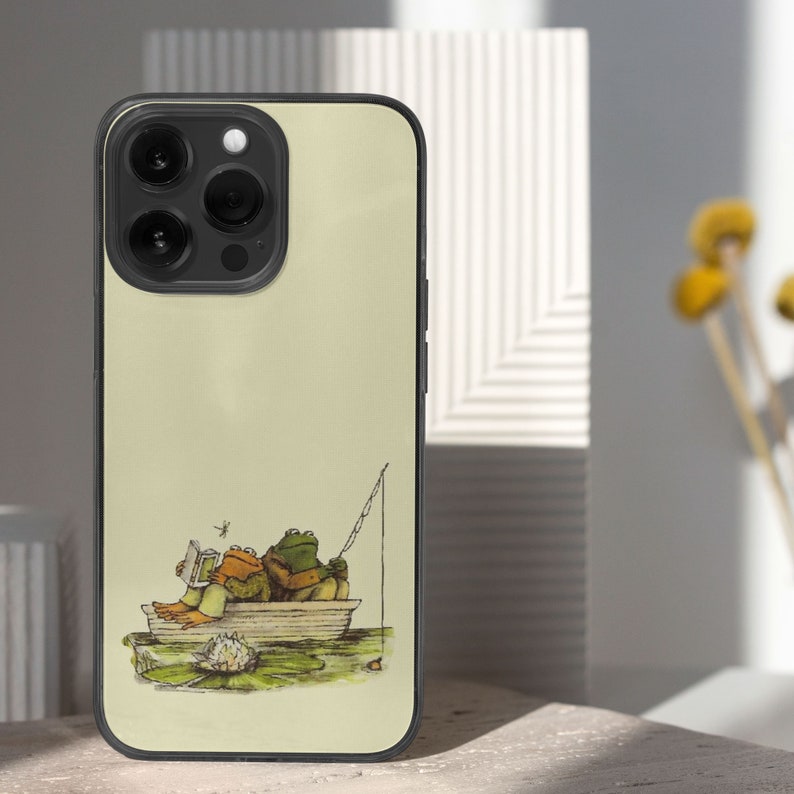 iPhone 15 Pro Max 14 Plus 13 12 11 clear case with Frog and Toad Aesthetic design on it, there are total of five phone cover options to choose from. Green cottage core, nature core, old children book, animals, pastel cover artworks are depcited.