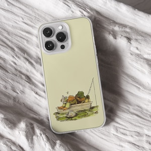 iPhone 15 Pro Max 14 Plus 13 12 11 clear case with Frog and Toad Aesthetic design on it, there are total of five phone cover options to choose from. Green cottage core, nature core, old children book, animals, pastel cover artworks are depcited.