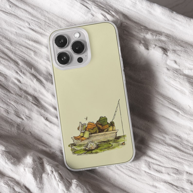 iPhone 15 Pro Max 14 Plus 13 12 11 clear case with Frog and Toad Aesthetic design on it, there are total of five phone cover options to choose from. Green cottage core, nature core, old children book, animals, pastel cover artworks are depcited.