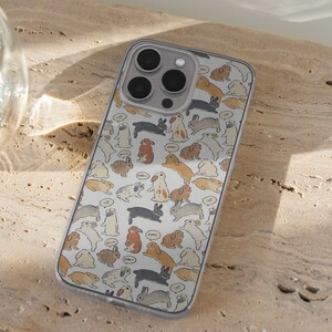 May include: A white iPhone case with a pattern of small, cartoon bunnies in various poses. The bunnies are in shades of brown, gray, and white. The case has a clear back and a black camera bump.