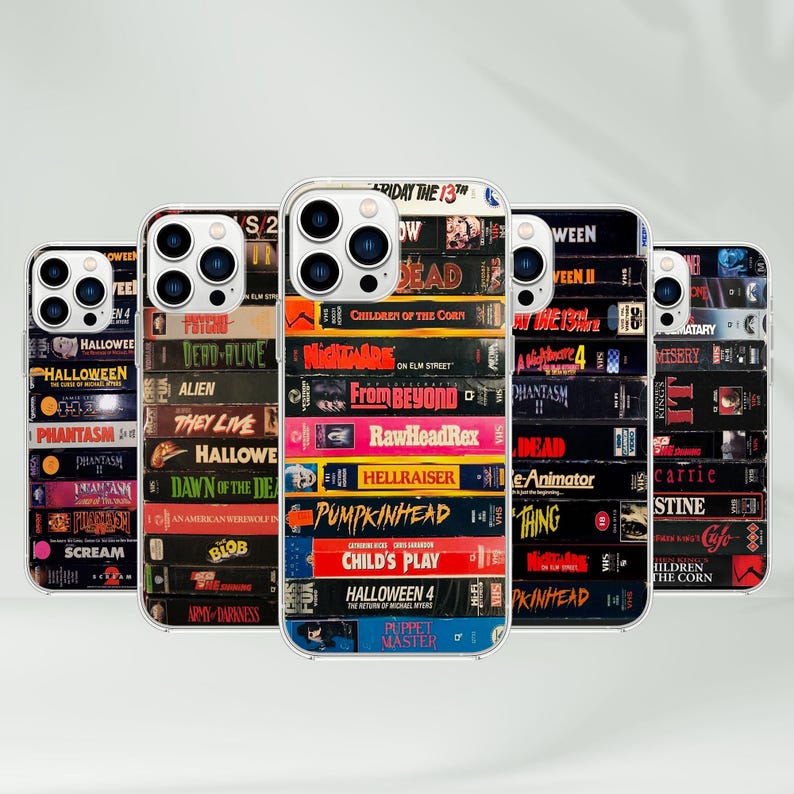 May include: Five phone cases with clear edges, each displaying a stack of VHS tapes with horror film titles such as "Halloween," "Nightmare on Elm Street," and "Child's Play." The cases are aligned.