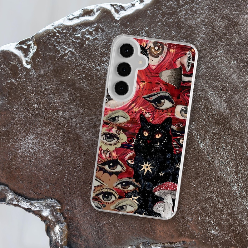 Puede incluir: Una funda transparente para tel&eacute;fono con un dise&ntilde;o colorido que presenta un gato negro, ojos y hongos. La funda tiene un fondo rojo, rosa y blanco con un ambiente psicod&eacute;lico.