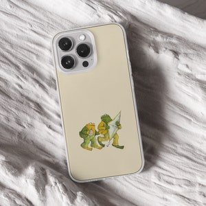 iPhone 15 Pro Max 14 Plus 13 12 11 clear case with Frog and Toad Aesthetic design on it, there are total of five phone cover options to choose from. Green cottage core, nature core, old children book, animals, pastel cover artworks are depcited.