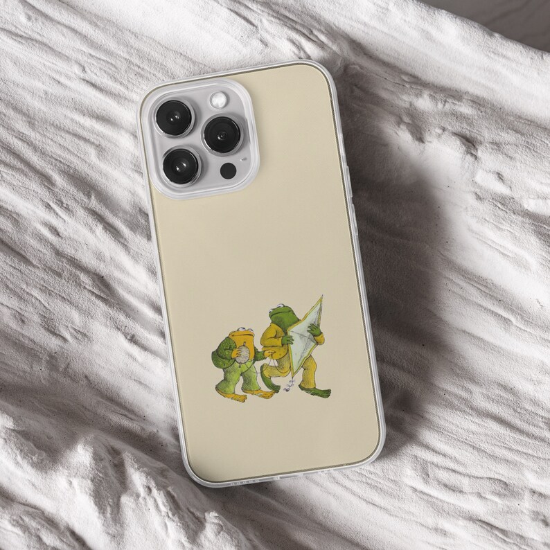 iPhone 15 Pro Max 14 Plus 13 12 11 clear case with Frog and Toad Aesthetic design on it, there are total of five phone cover options to choose from. Green cottage core, nature core, old children book, animals, pastel cover artworks are depcited.