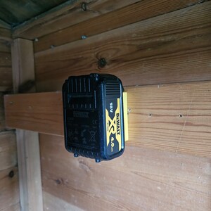 May include: A black and yellow DeWalt XR 18V 4.0 Ah lithium-ion battery is mounted on a wooden wall.