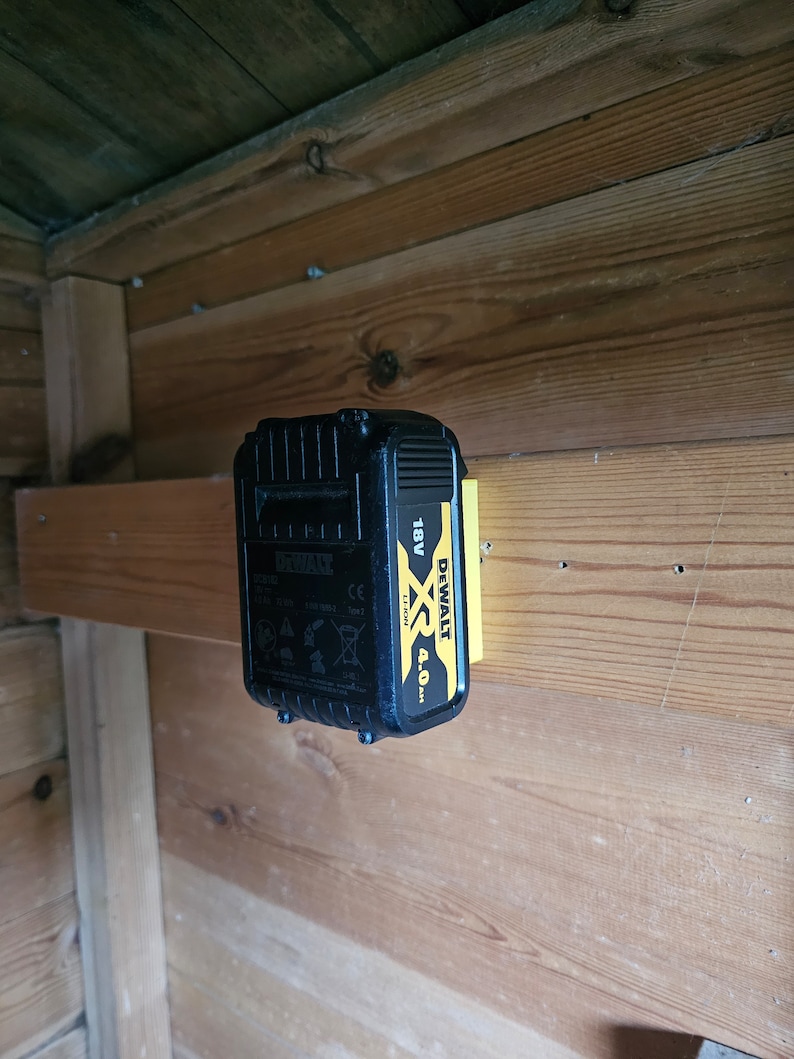 May include: A black and yellow DeWalt XR 18V 4.0 Ah lithium-ion battery is mounted on a wooden wall.