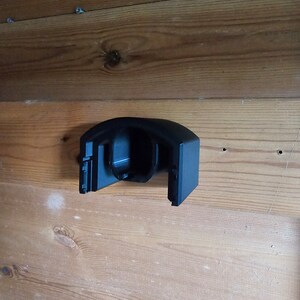 Op de afbeelding: Zwarte plastic wandbeugel met een gebogen ontwerp. De beugel heeft een ronde opening in het midden.