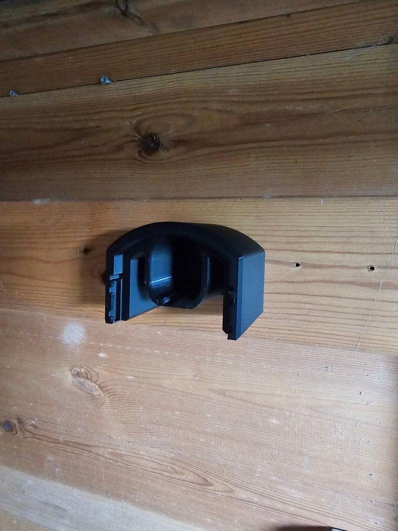 Op de afbeelding: Zwarte plastic wandbeugel met een gebogen ontwerp. De beugel heeft een ronde opening in het midden.