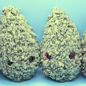 May include: Four plush, cone-shaped creatures with textured, gray-green fur. Each has large, round, glittery eyes with pink or gold accents. The toys are arranged in a row against a light blue background, creating a whimsical, playful scene.