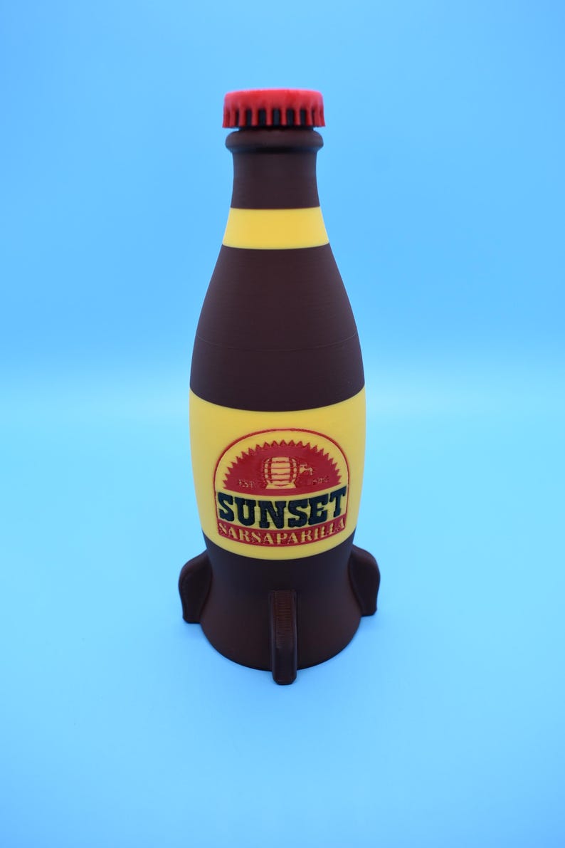 May include: A brown glass bottle with a red cap and yellow stripes. The bottle is shaped like a rocket and has a label that says "Sunset Sarsaparilla".