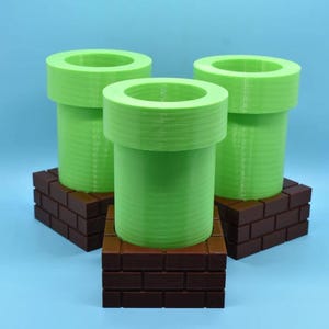 May include: Three green plastic pipes with brown brick bases. The pipes are shaped like the iconic Super Mario Bros. pipes.