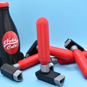 May include: A black Nuka Cola bottle with a red and white label, and several red and black bottle openers. The bottle openers have a red handle and a black and gray base. The items are on a blue background.