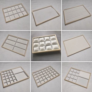 Puede incluir: Conjunto de nueve bandejas de joyería de madera de diferentes tamaños con forro de fieltro blanco. Las bandejas son perfectas para organizar y exhibir anillos, aretes, collares y otras joyas.
